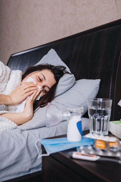 ベッドで薬を飲む若い病気の女性