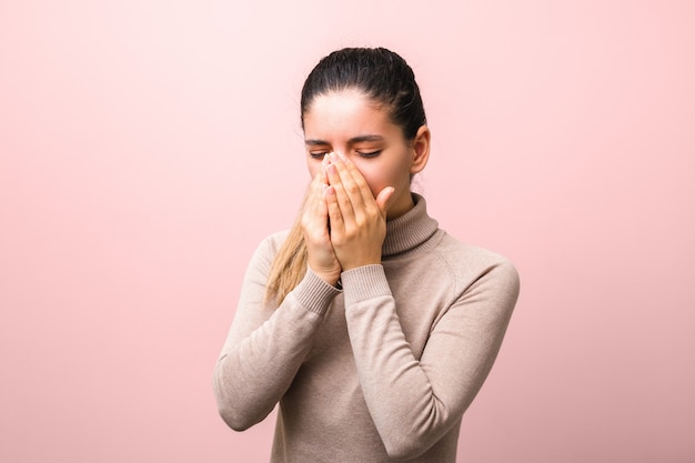 Young sick woman with fly or virus sneezing and coughing in a mask or napkin looking very hopeless