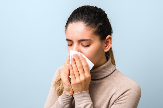 young sick woman with virus sneezing and coughing in a napkin