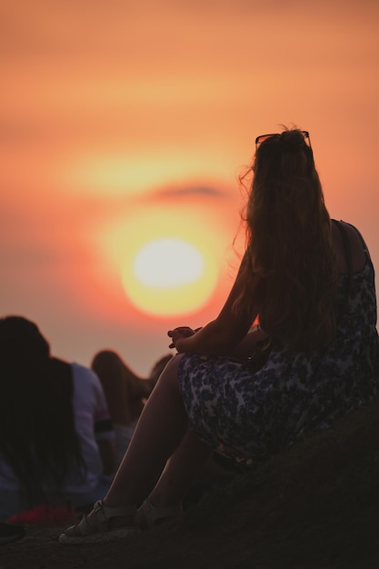 Young silhouetted girl sitting and enjoying evening sun set view