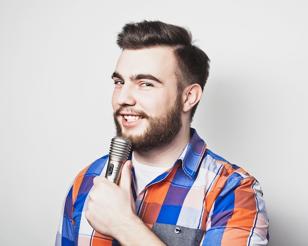 Young singer man  with microphone over grey background