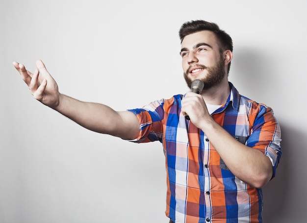 Young singer man  with microphone over grey background