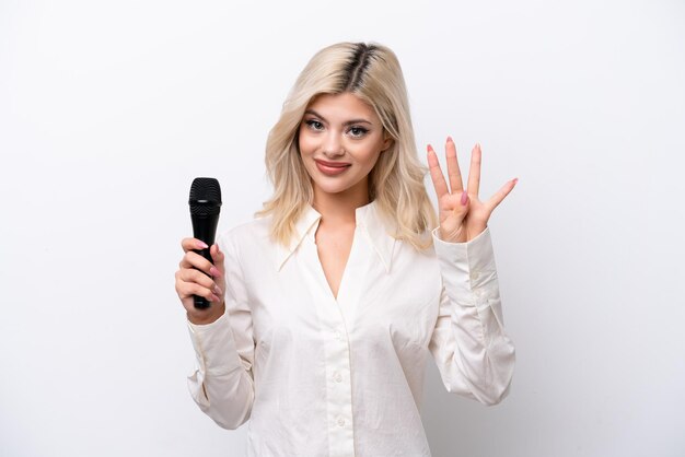 Young singer woman picking up a microphone isolated on white background happy and counting four with fingers