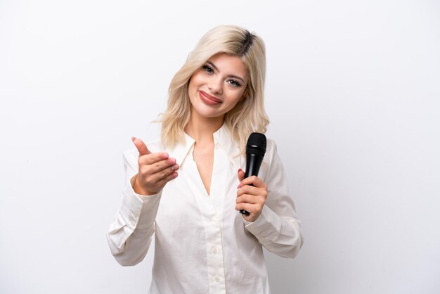 Young singer woman picking up a microphone isolated on white background shaking hands for closing a good deal