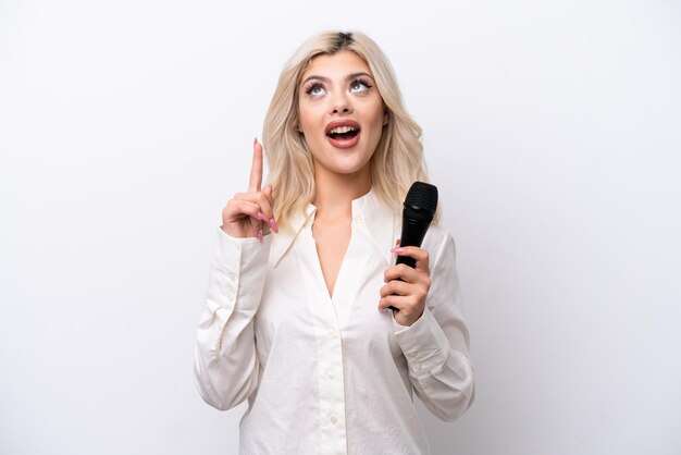 Young singer woman picking up a microphone isolated on white background thinking an idea pointing the finger up