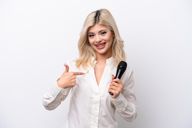 Young singer woman picking up a microphone isolated on white background with surprise facial expression