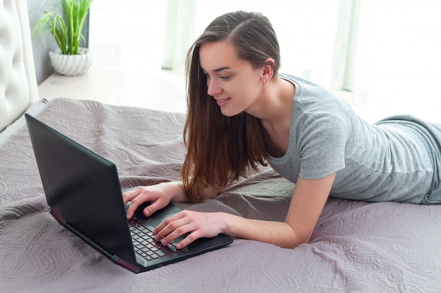 Giovane ragazza single che utilizza un laptop per chattare sui social network e trovare amore, partner e fidanzato a casa. incontri online. trascorrere del tempo libero online