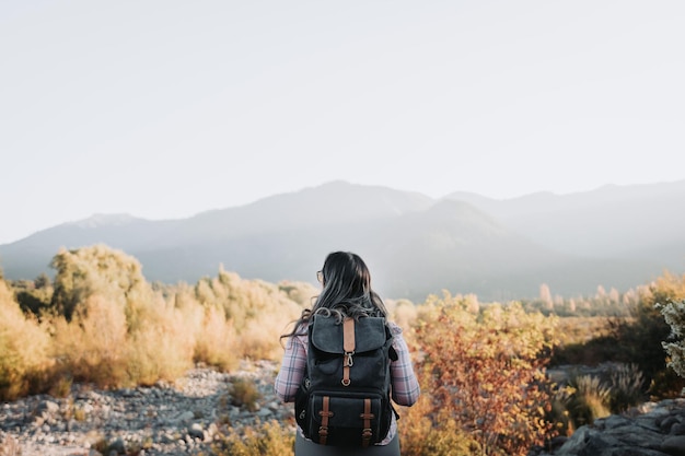 自然の中でトレッキングをしている谷を見てバックパックを持った若い独身旅行者の女性