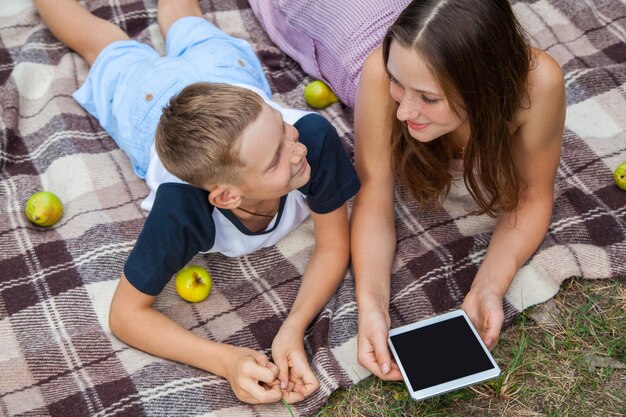 Young sister and brother lying down and work with tablet