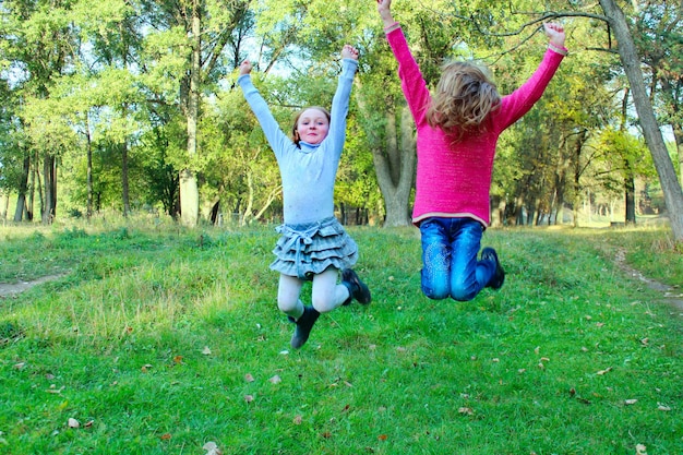 Foto le giovani sorelle saltano nel parco felice infanzia vaga nell'aria