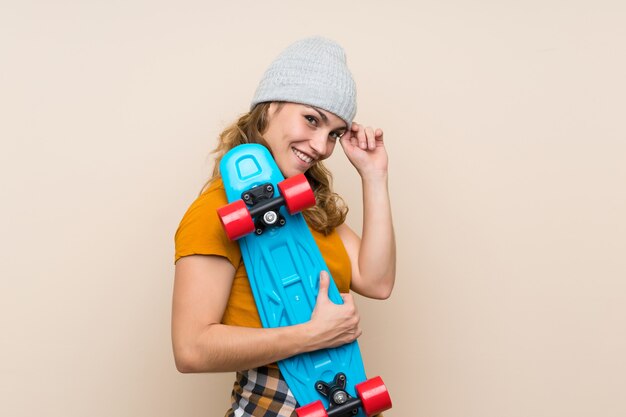 Young skater blonde girl over isolated wall