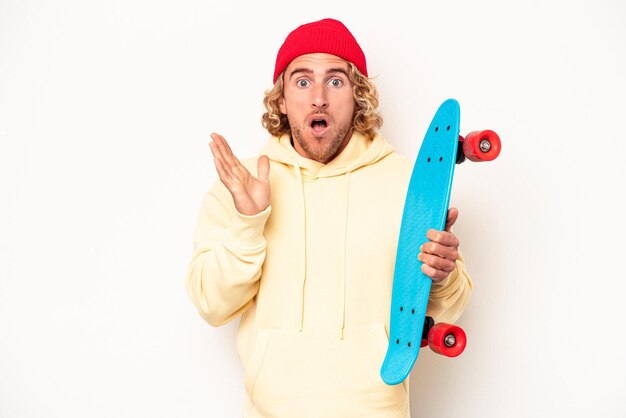 Young skater caucasian man isolated on white background surprised and shocked.