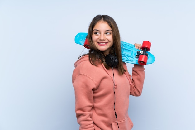 Young skater girl over isolated wall