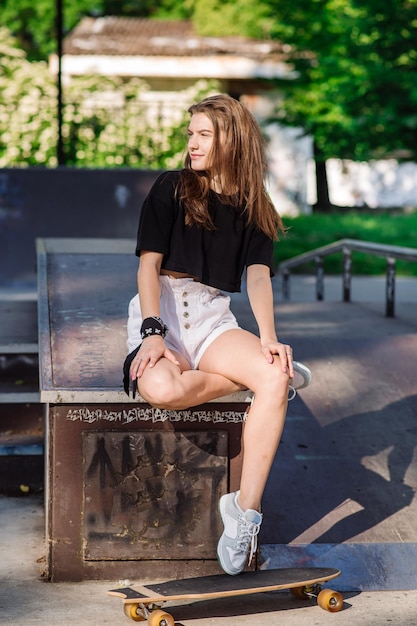 Young skater girl resting with a skateboard in the skaters park