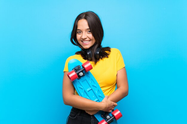 孤立した青い背景上の若いスケーター女性