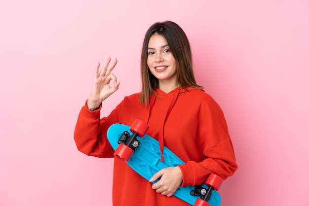 Young skater woman over isolated pink background