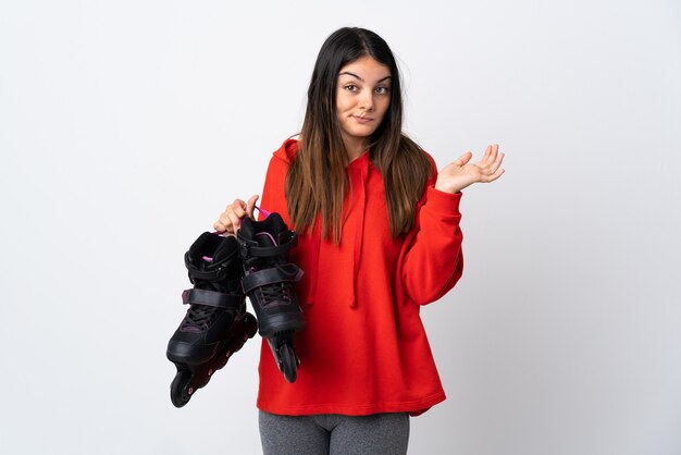 Young skater woman isolated on white having doubts while raising hands