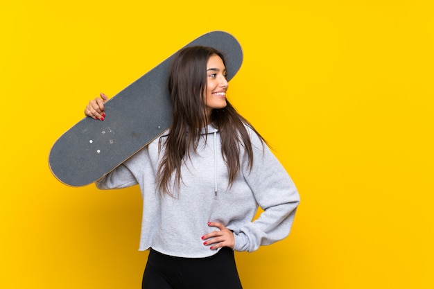 Young skater woman over isolated yellow wall