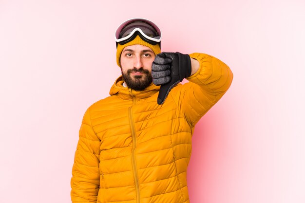 Изолированный человек молодого лыжника показывающ жест нелюбов, большие пальцы руки вниз. Концепция несогласия.