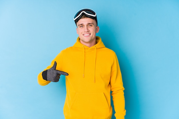 Young skier man person pointing by hand to a shirt copy space, proud and confident