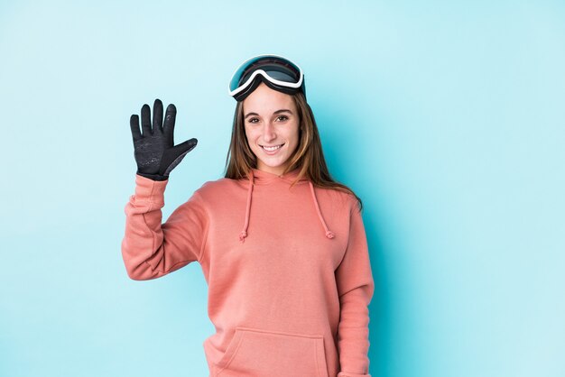 Young skier woman isolated smiling cheerful showing number five with fingers.