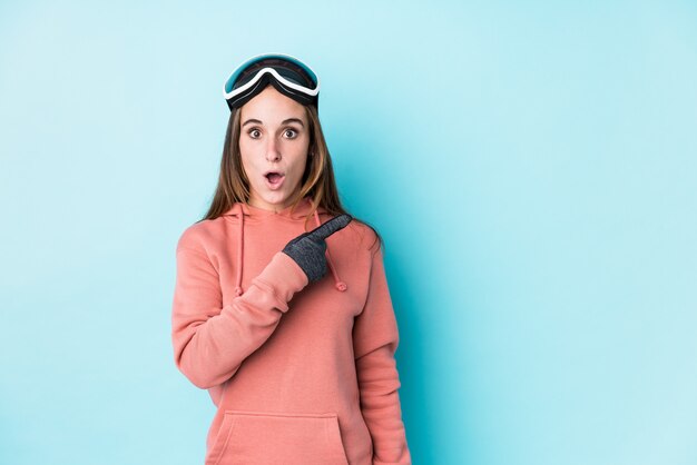 Young skier woman pointing to the side