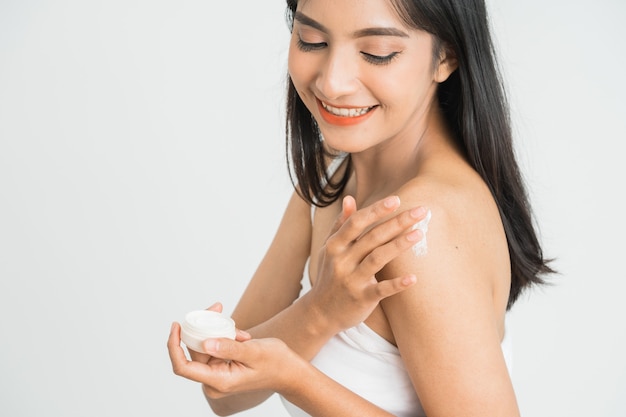 Young skin care asian woman applying body lotion on arm and shoulder