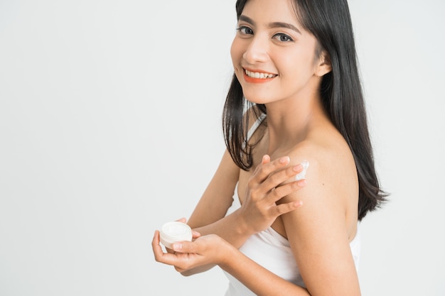 Young skin care asian woman applying body lotion on arm and shoulder