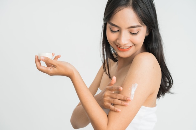 Photo young skin care asian woman applying body lotion on arm and shoulder