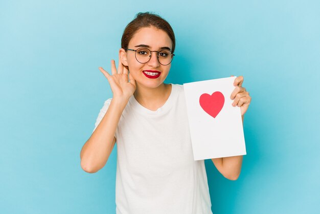 Young skinny arab girl holding a valentines day card trying to listening a gossip.