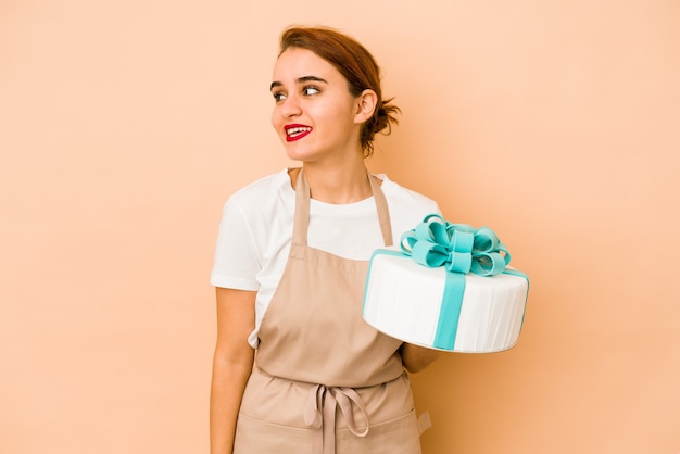 Young skinny arab pastry chef woman looks aside smiling, cheerful and pleasant.