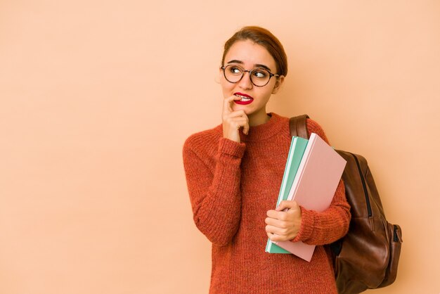 若い細いアラブの学生女性は、コピースペースを見ている何かについて考えてリラックスしました。