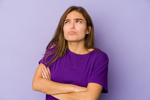 Young skinny caucasian girl teenager on purple background tired of a repetitive task.