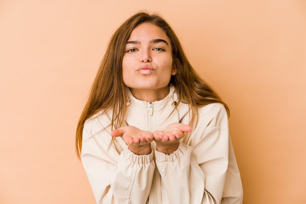 Young skinny caucasian teenager girl folding lips and holding palms to send air kiss.