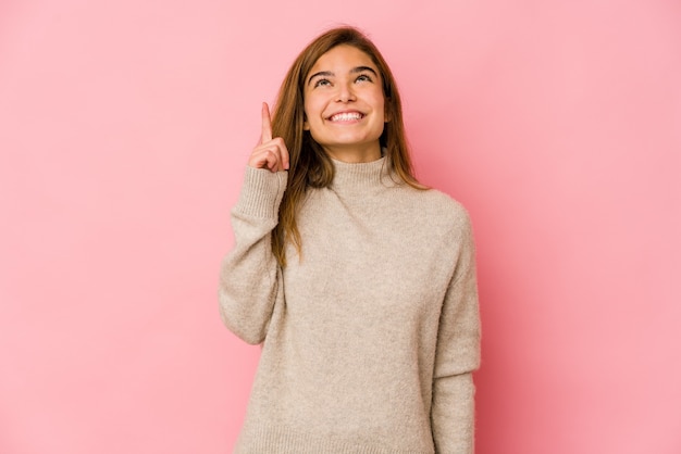 Young skinny caucasian teenager girl indicates with both fore fingers up showing a blank space.