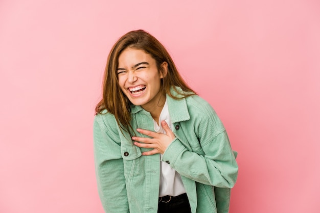 Young skinny caucasian teenager girl laughs out loudly keeping hand on chest.