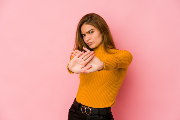 Young skinny caucasian teenager girl standing with outstretched hand showing stop sign, preventing you.