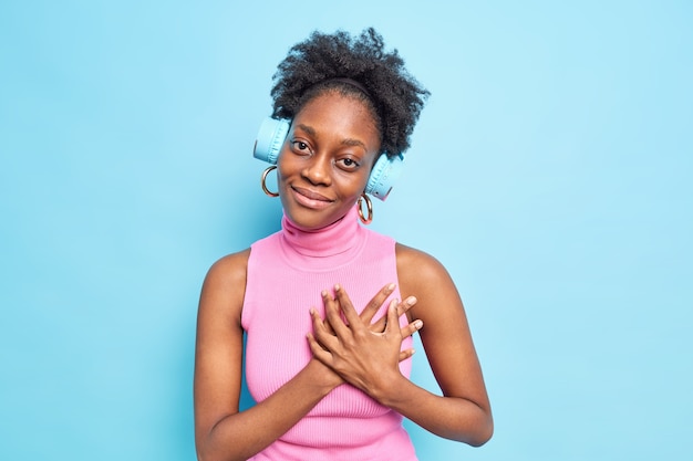 Young skinny dark skinned woman demonstrates her heartleft gratitude clasps hands to heart being thankful for 