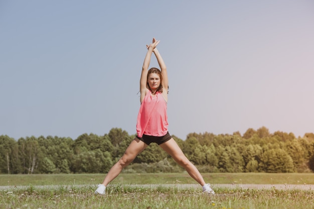 Young skinny girl doing exercise on the grass.