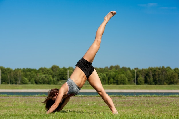 Young skinny girl doing exercise on the grass.