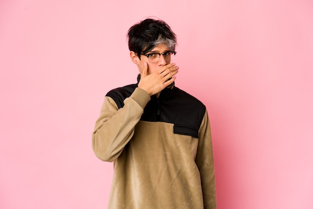 Young skinny hispanic man covering mouth with hands looking worried.