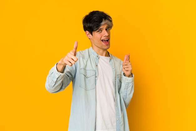 Young skinny hispanic man pointing to front with fingers.