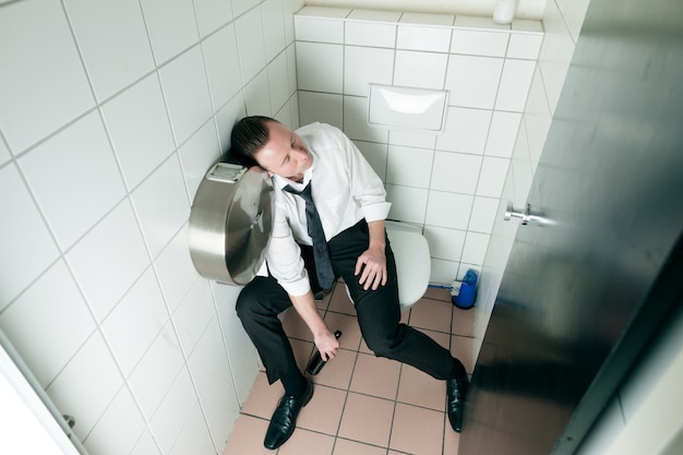 Young sleeping drunk man on the toilette