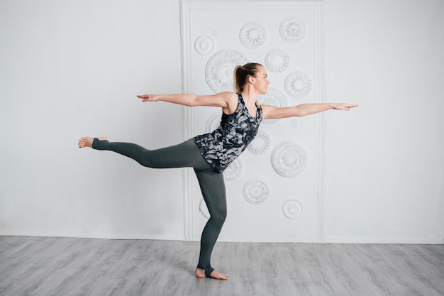 Young slender girl athlete performs fitness exercises and yoga