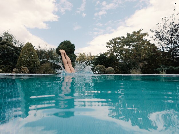 Giovane ragazza snella in costume da bagno rosso si tuffa in piscina