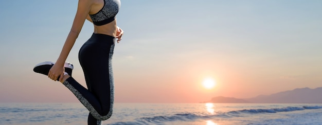 A young slim athletic girl in sportswear performs a set of exercises on the background of mountains