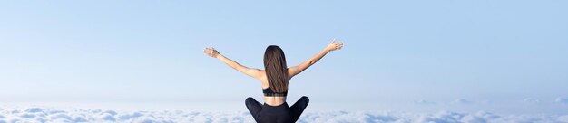 A young slim athletic girl in sportswear performs a set of exercises Fitness and healthy lifestyle against the background of clouds sky