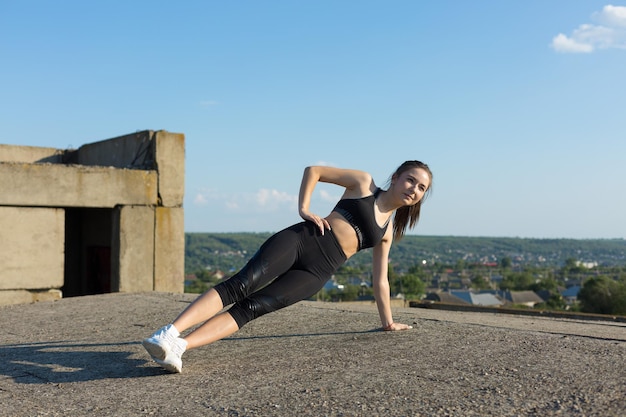 A young slim athletic girl in sportswear performs a set of exercises