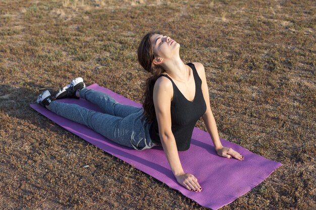 A young slim athletic girl in sportswear with snakeskin prints performs a set of exercises. Fitness and healthy lifestyle.