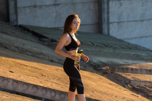 Молодая стройная спортивная девушка в спортивной одежде с принтами из змеиной кожи выполняет комплекс упражнений